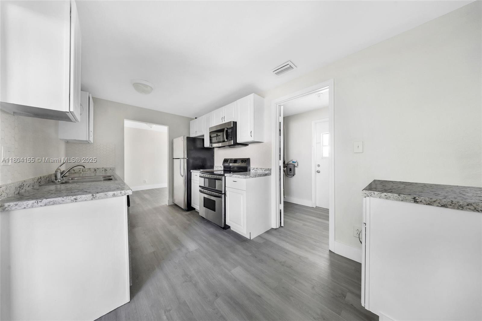 2520 Northwest 2nd Drive Pompano Beach, FL 33064 - Photo 3 of 20 a kitchen with granite countertop a refrigerator and a stove top oven