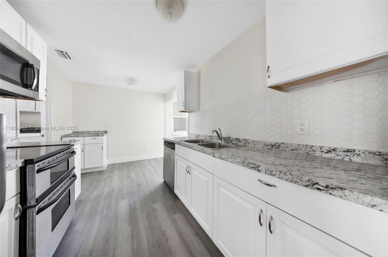 2520 Northwest 2nd Drive Pompano Beach, FL 33064 - Photo 4 of 20 a kitchen with granite countertop a sink wooden floor and stainless steel appliances