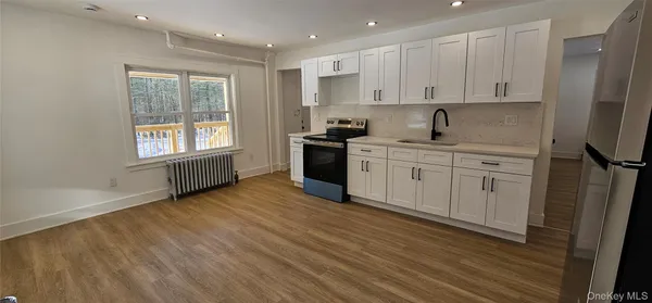 a kitchen with stainless steel appliances granite countertop a stove a sink and white cabinets