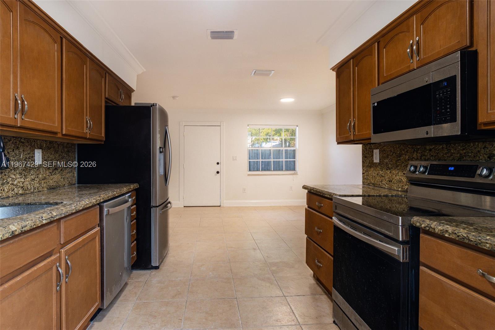 1518 Northwest 65th Street Miami, FL 33147 - Photo 9 of 28 a kitchen with stainless steel appliances granite countertop a stove top oven a sink dishwasher and a refrigerator with wooden cabinets