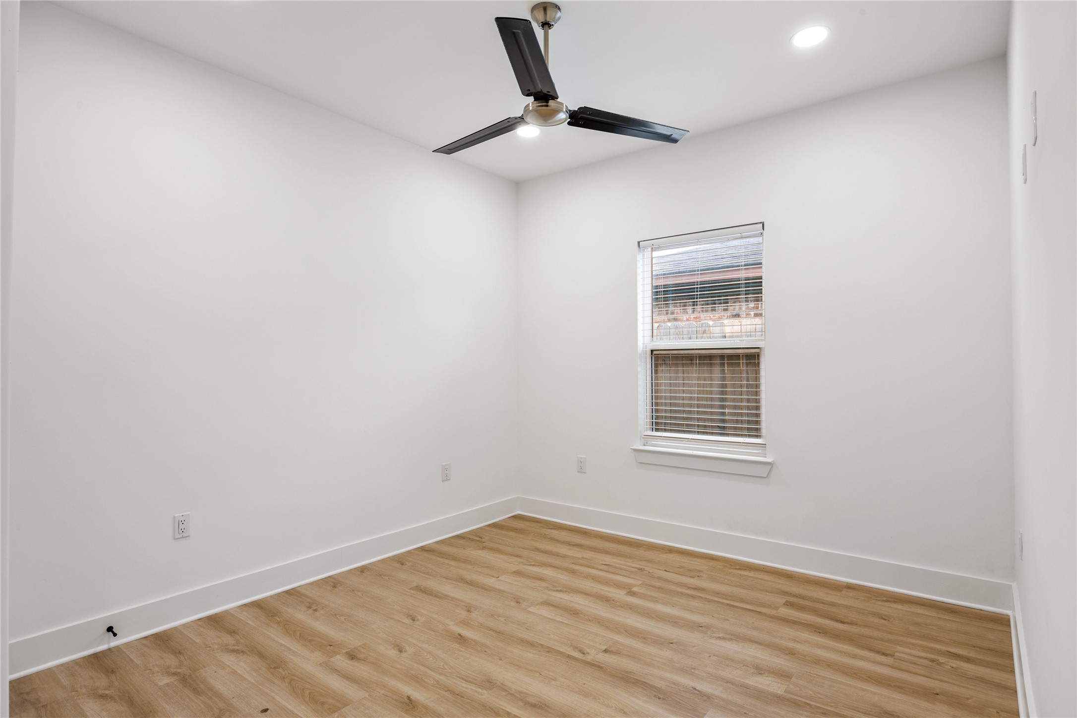 1121 Austin Street Rosenberg, TX 77471 - Photo 10 of 44 This room features bright white walls, a modern ceiling fan, luxury vinyl flooring, and a window with blinds, providing a clean and versatile space.