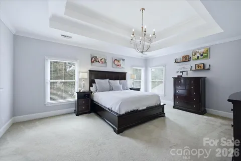 a spacious bedroom with a bed chandelier and window
