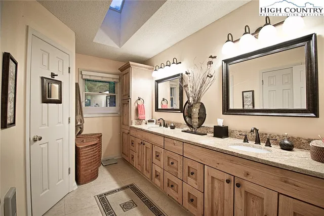 a bathroom with double vanity sink a two mirror a window and a shower