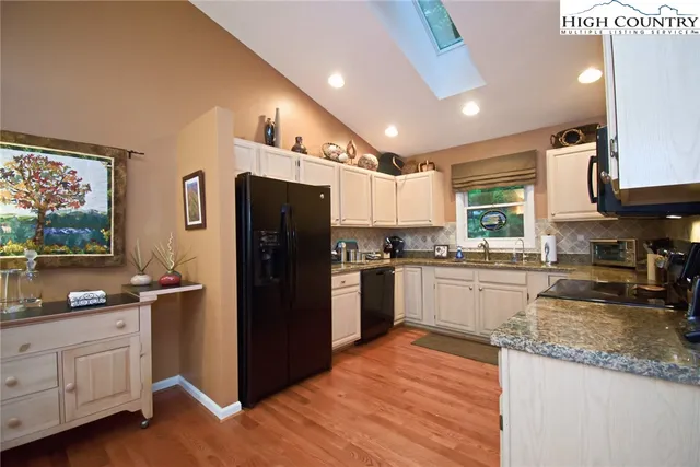 a kitchen with granite countertop a refrigerator stove top oven and sink