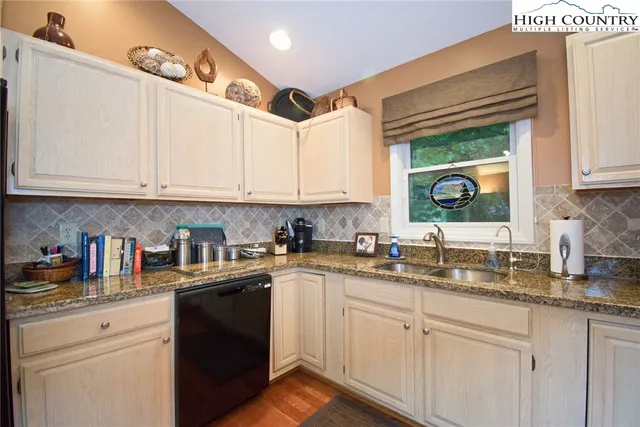 a kitchen with granite countertop white cabinets white stainless steel appliances and sink