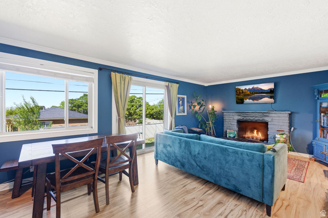 935 900 North Bountiful, UT 84010 - Photo 16 of 46 Living room featuring light wood-style flooring, a stone fireplace, a textured ceiling, and crown molding