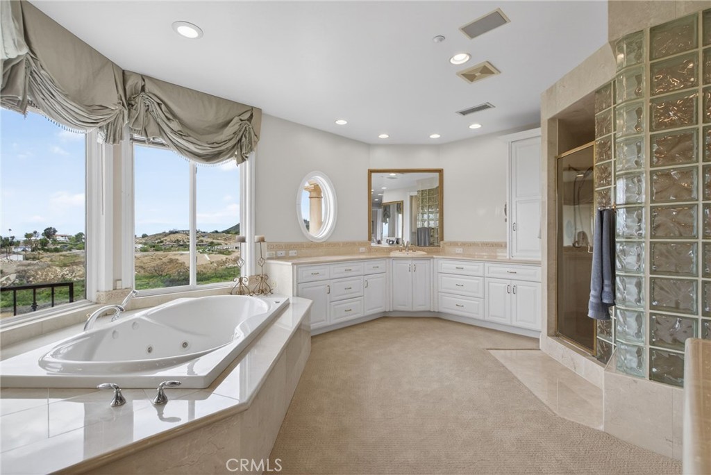 6952 Royal Hunt Ridge Drive Riverside, CA 92506 - Photo 40 of 75 a bathroom with a tub a sink and a large mirror