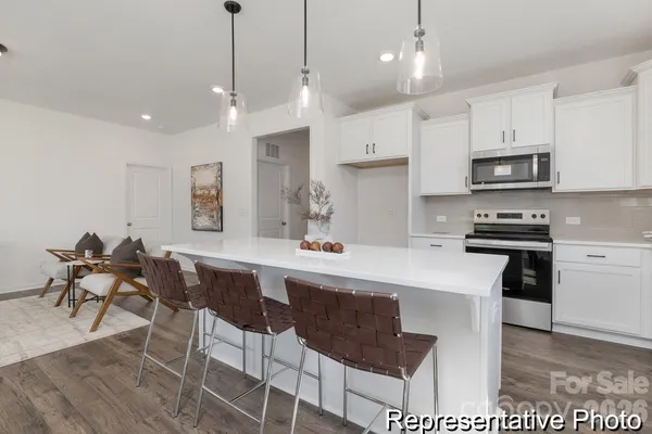 a kitchen with stainless steel appliances kitchen island granite countertop a sink a stove a dining table and chairs