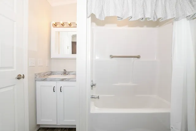 a bathroom with a granite countertop sink a mirror and a bathtub