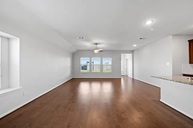 an empty room with wooden floor and windows