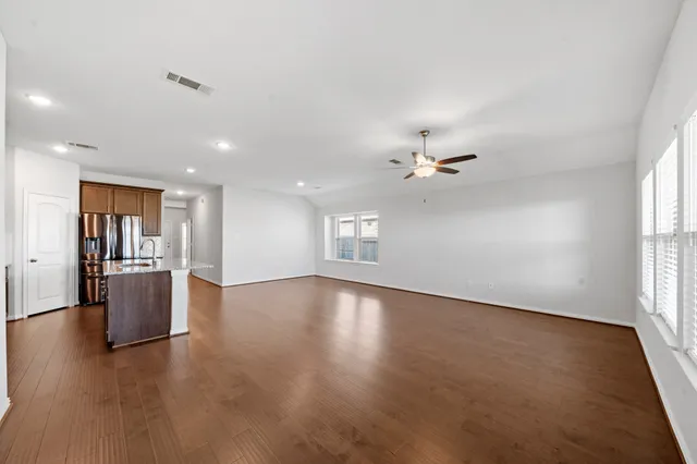 a view of an empty room with window and wooden floor