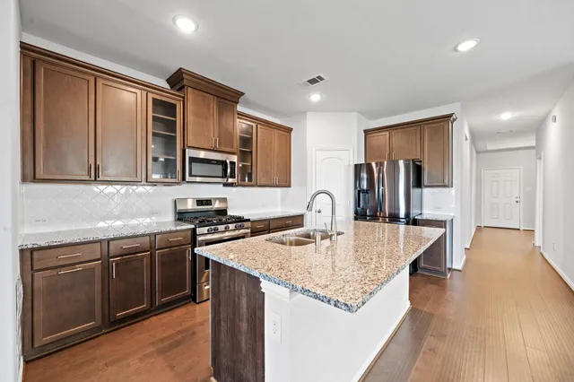 a kitchen with stainless steel appliances granite countertop a sink dishwasher stove and refrigerator