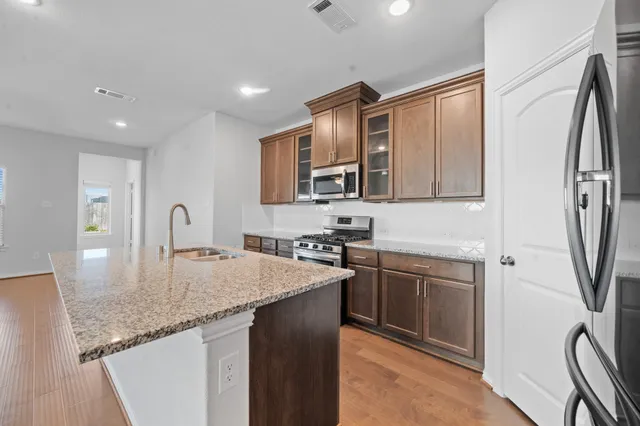 a kitchen with stainless steel appliances granite countertop a sink a stove and a refrigerator