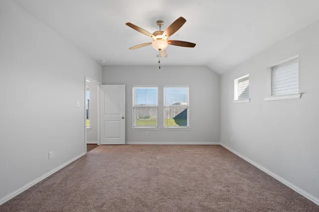 an empty room with windows and ceiling fan