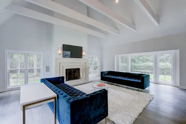 a living room with a fireplace a flat screen tv and a large window