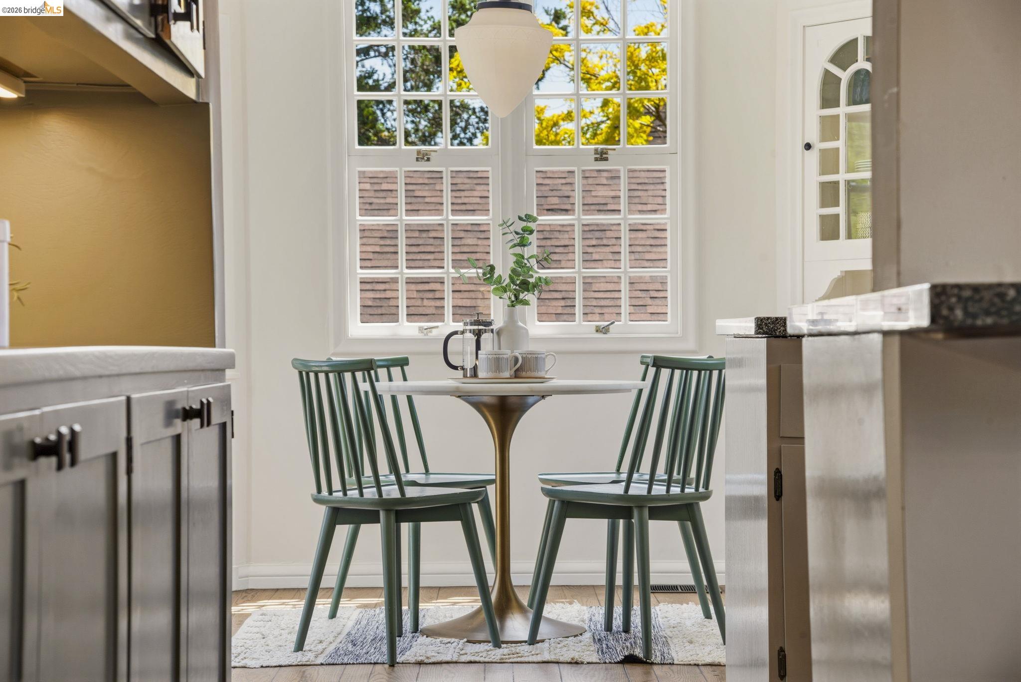 1087 Hubert Road Oakland, CA 94610 - Photo 51 of 67 Bright dining nook with a white double-hung window featuring multiple panes, an overhead pendant light, light-colored walls, and wood-finish flooring