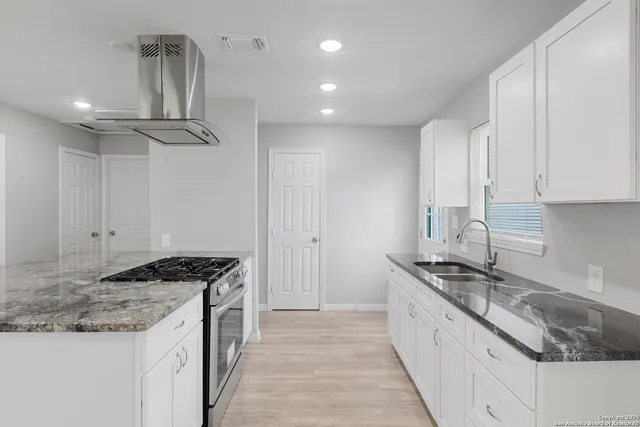 a kitchen with stainless steel appliances granite countertop a sink stove and cabinets