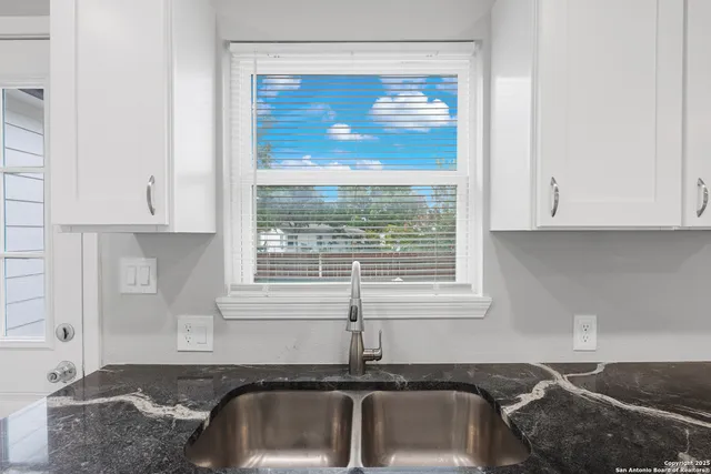 a kitchen with granite countertop white cabinets and a sink