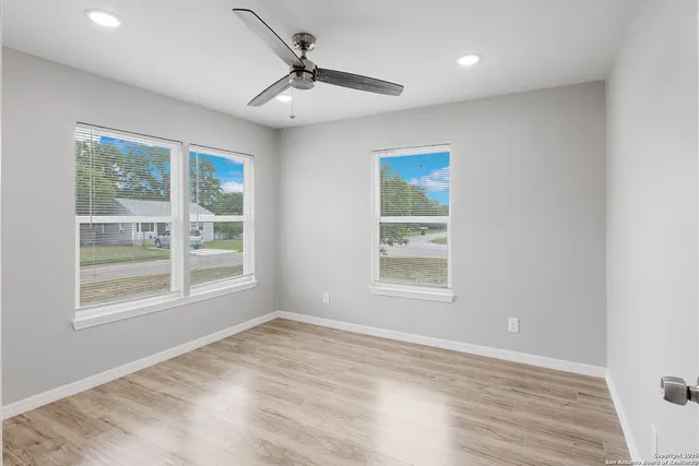 an empty room with wooden floor chandelier and windows