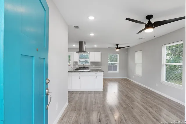 a open kitchen with white cabinets and wooden floor