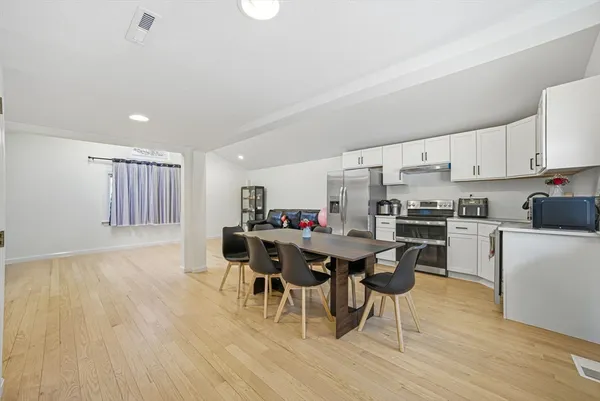 a kitchen with a dining table chairs and white appliances