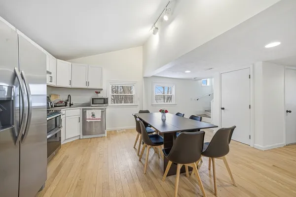 a kitchen with stainless steel appliances kitchen island granite countertop a dining table chairs and a refrigerator