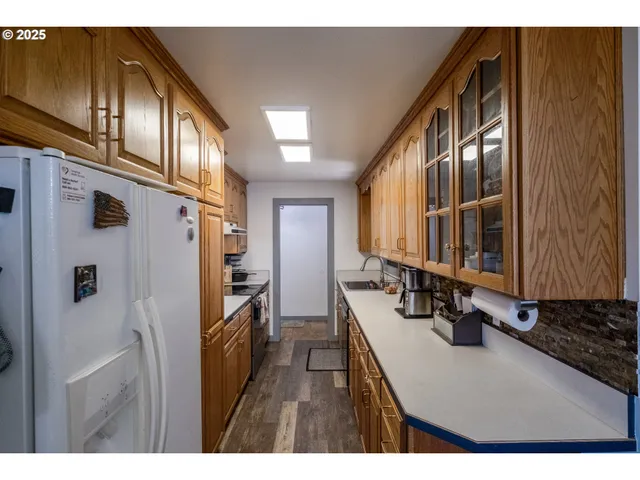 a kitchen with stainless steel appliances a refrigerator a sink and wooden cabinets