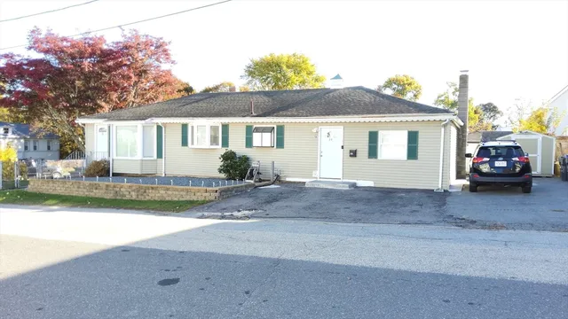 a view of a white house next to a yard with a large tree