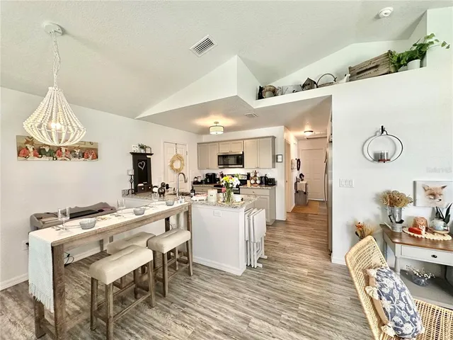 a view of a dining room and livingroom with furniture wooden floor a chandelier