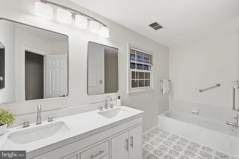 a bathroom with a sink double vanity granite tub shower and a mirror