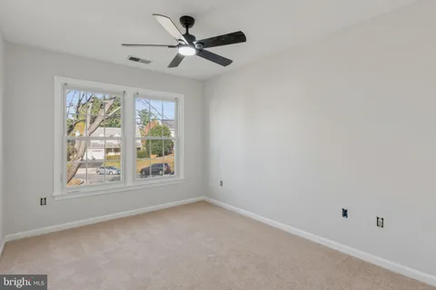 an empty room with windows and ceiling fan