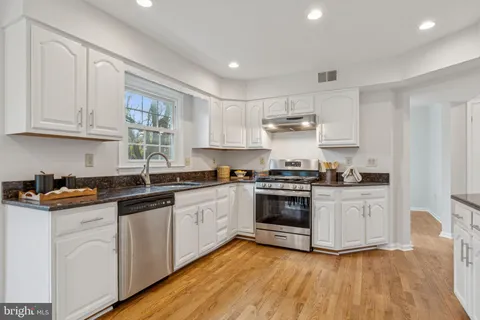 a kitchen with granite countertop white cabinets and white appliances