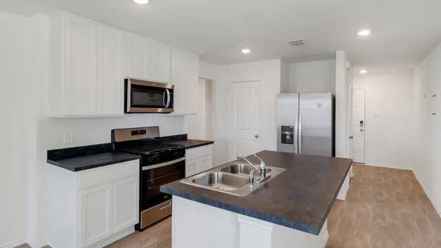 a kitchen with stainless steel appliances granite countertop a stove a sink and a refrigerator