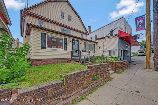 a view of a house with a small yard and a large tree