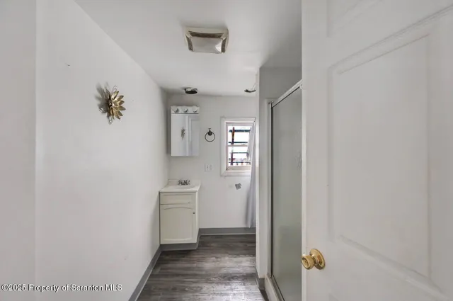 a view of a hallway view with wooden floor and a bathroom