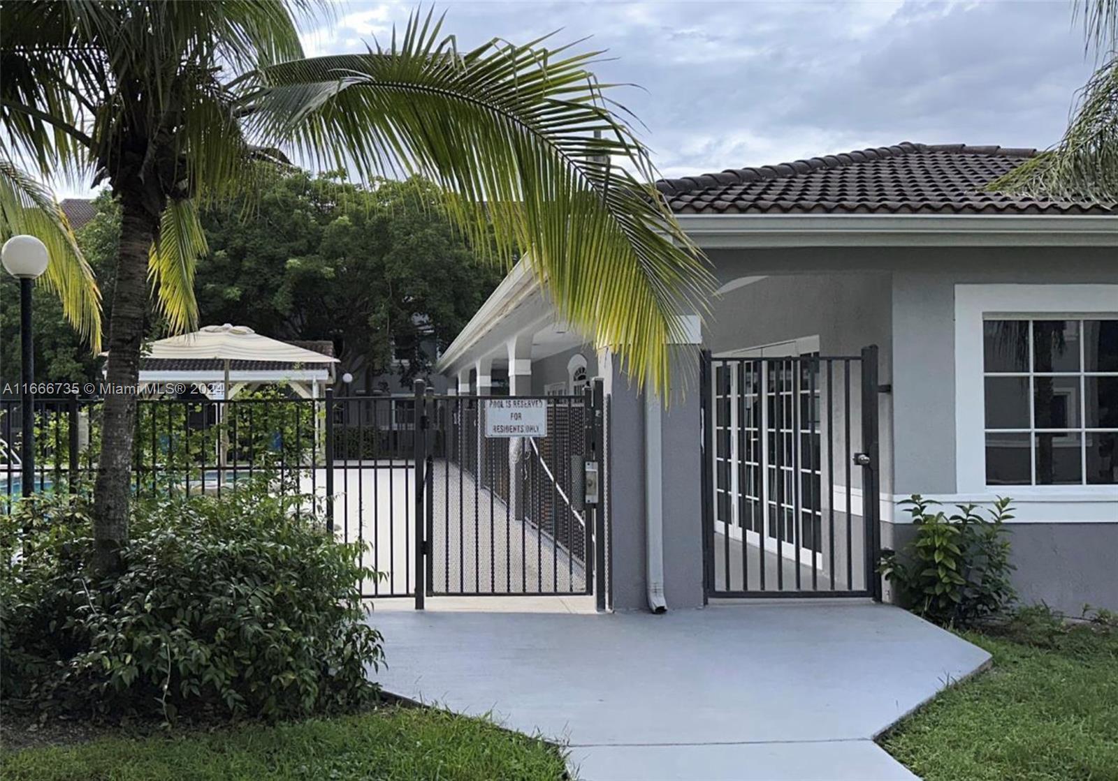 15430 Southwest 284th Street, Unit 6202 Homestead, FL 33033 - Photo 17 of 17 a view of a house with a yard and table and chairs under an umbrella