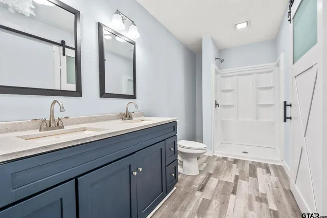 a spacious bathroom with a granite countertop sink toilet a mirror and shower