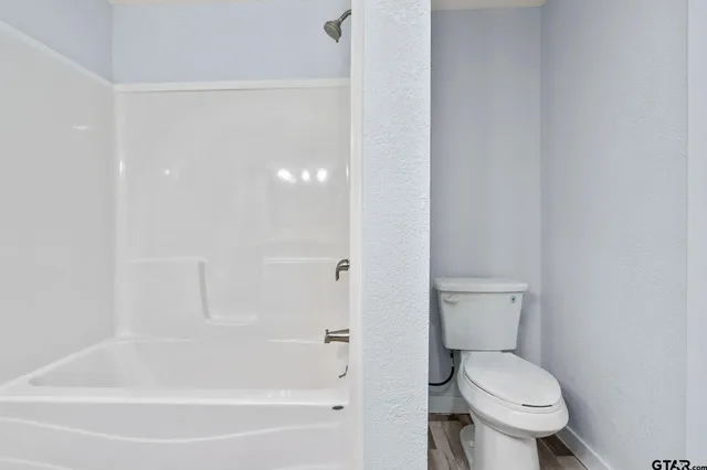 a white toilet sitting next to a bath tub