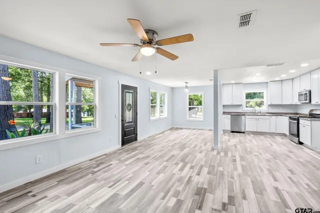 a view of an empty room with window and wooden floor