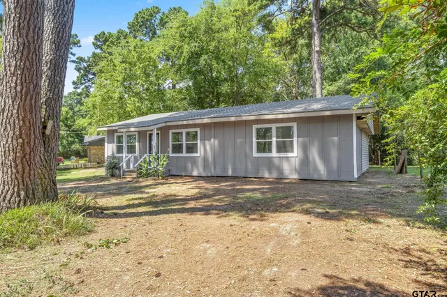 a view of a house with a yard and large tree