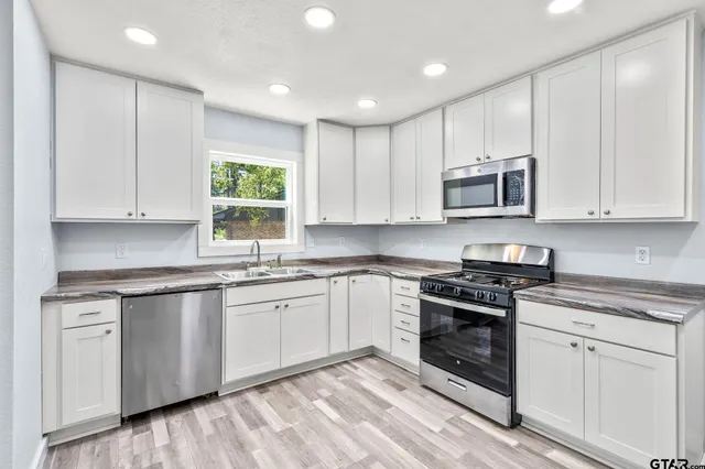 a kitchen with stainless steel appliances granite countertop a stove a sink and a microwave