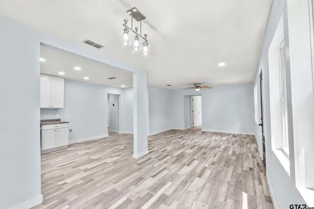 a view of a big room with wooden floor and a kitchen