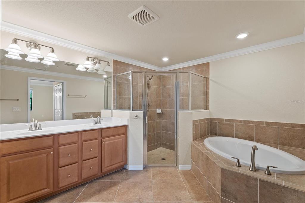 20080 Ragazza Circle, Unit 102 Venice, FL 34293 - Photo 26 of 49 a spacious bathroom with a double vanity sink a large mirror and a bathtub