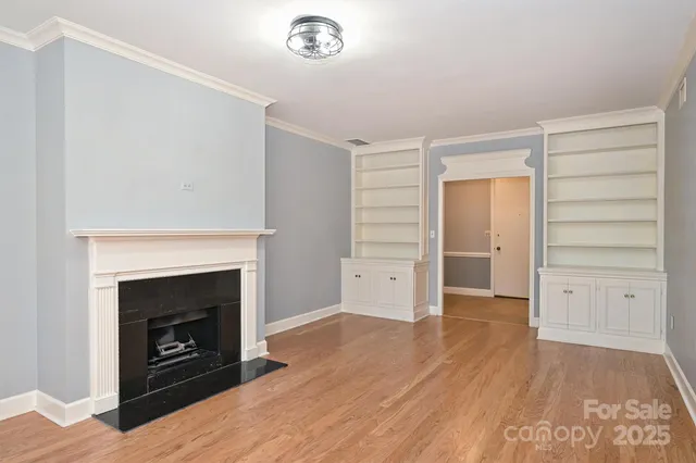 an empty room with wooden floor fireplace and windows