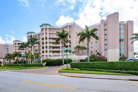 a front view of a multi story residential apartment building with yard and green space