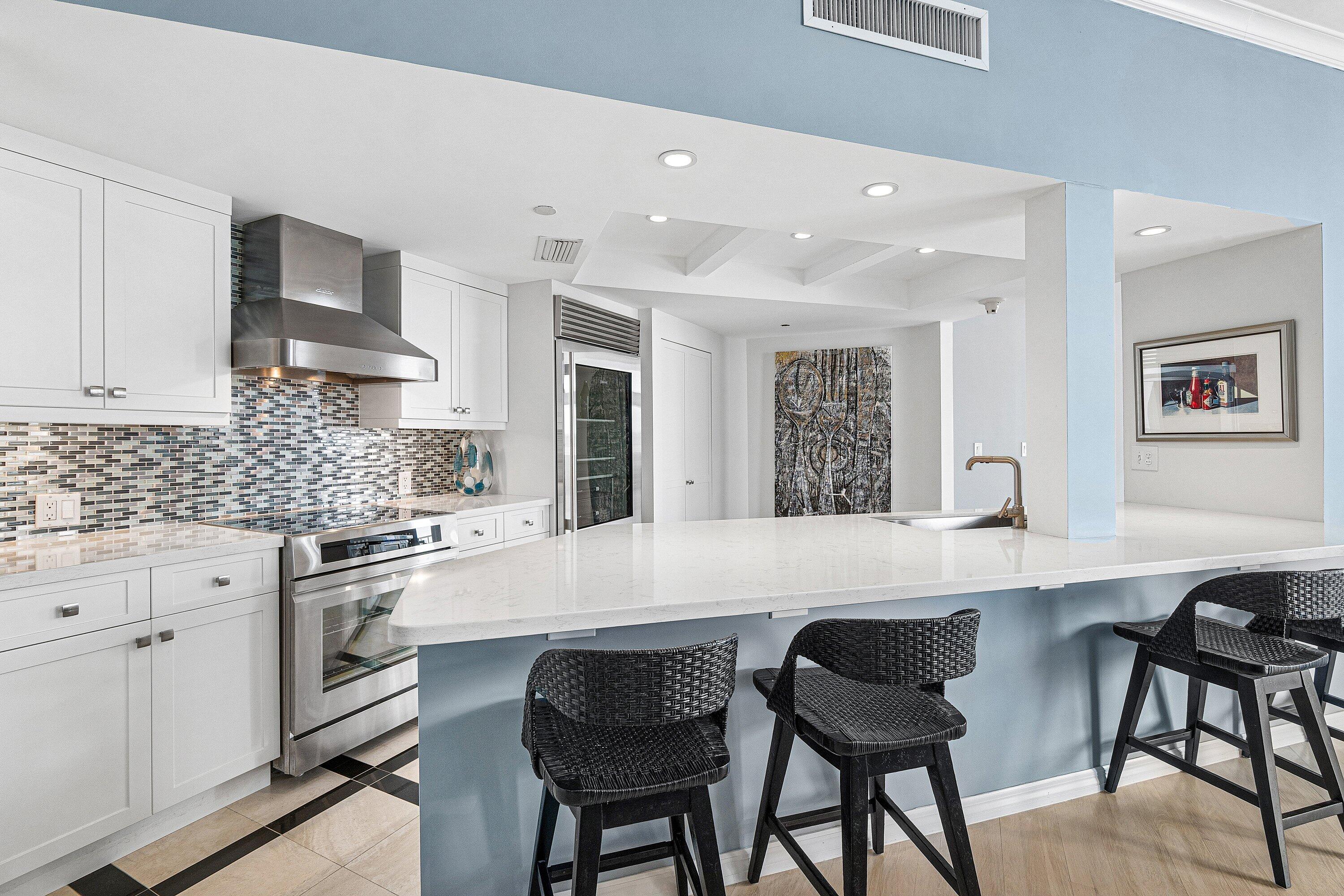 300 Southeast 5th Avenue, Unit PH 8120 Boca Raton, FL 33432 - Photo 10 of 54 a large white kitchen with stainless steel appliances granite countertop a stove a sink a table and chairs