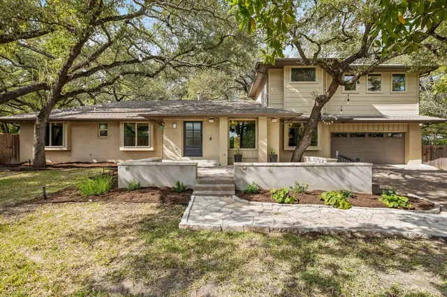 a view of a house with a yard and large tree