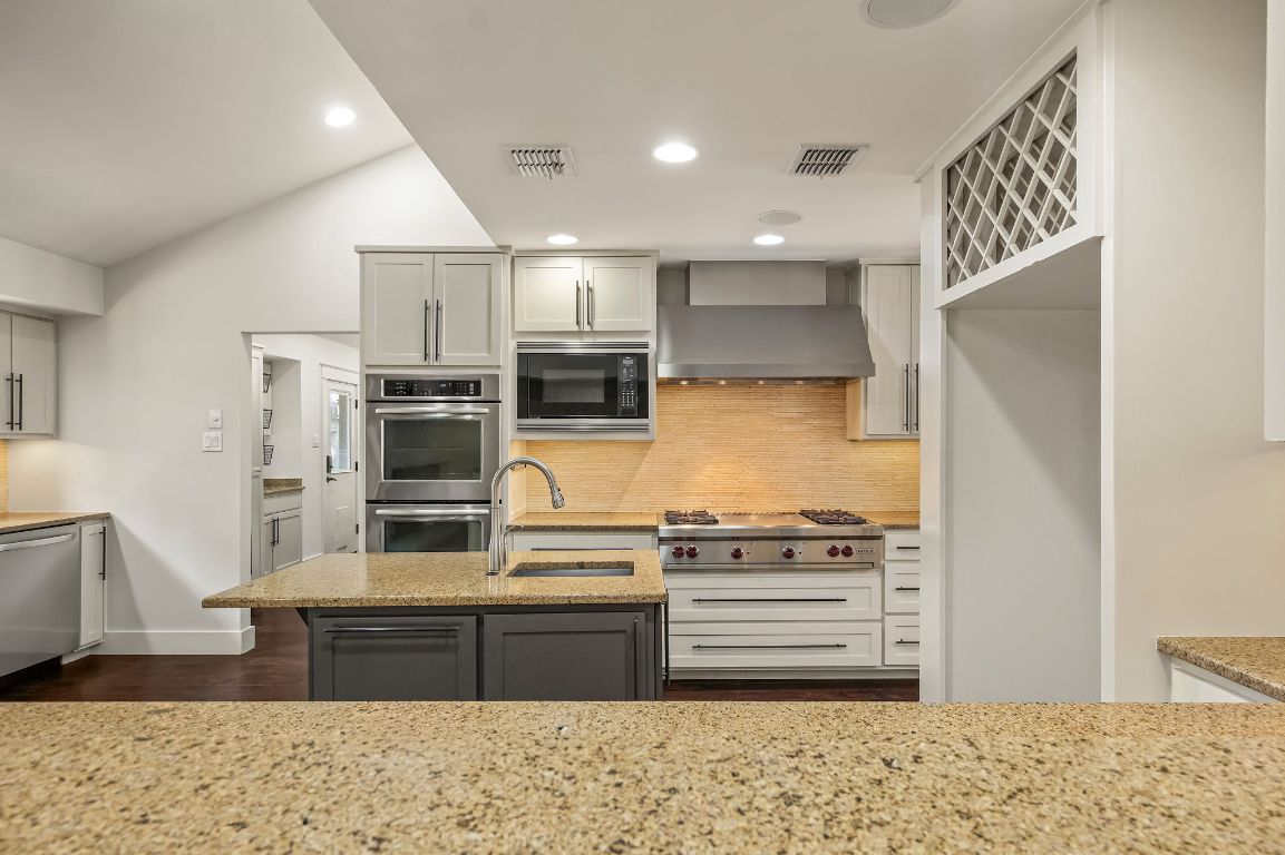 7202 Running Rope Circle Austin, TX 78731 - Photo 11 of 40 a kitchen with stainless steel appliances kitchen island granite countertop a refrigerator and a stove top oven