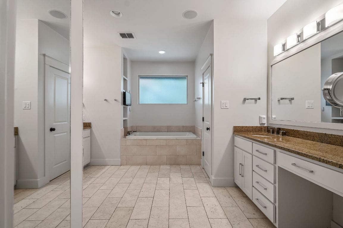 7202 Running Rope Circle Austin, TX 78731 - Photo 33 of 40 a spacious bathroom with a granite countertop sink a mirror and a bathtub