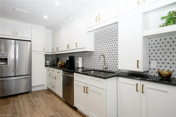a kitchen with granite countertop a sink stainless steel appliances and cabinets